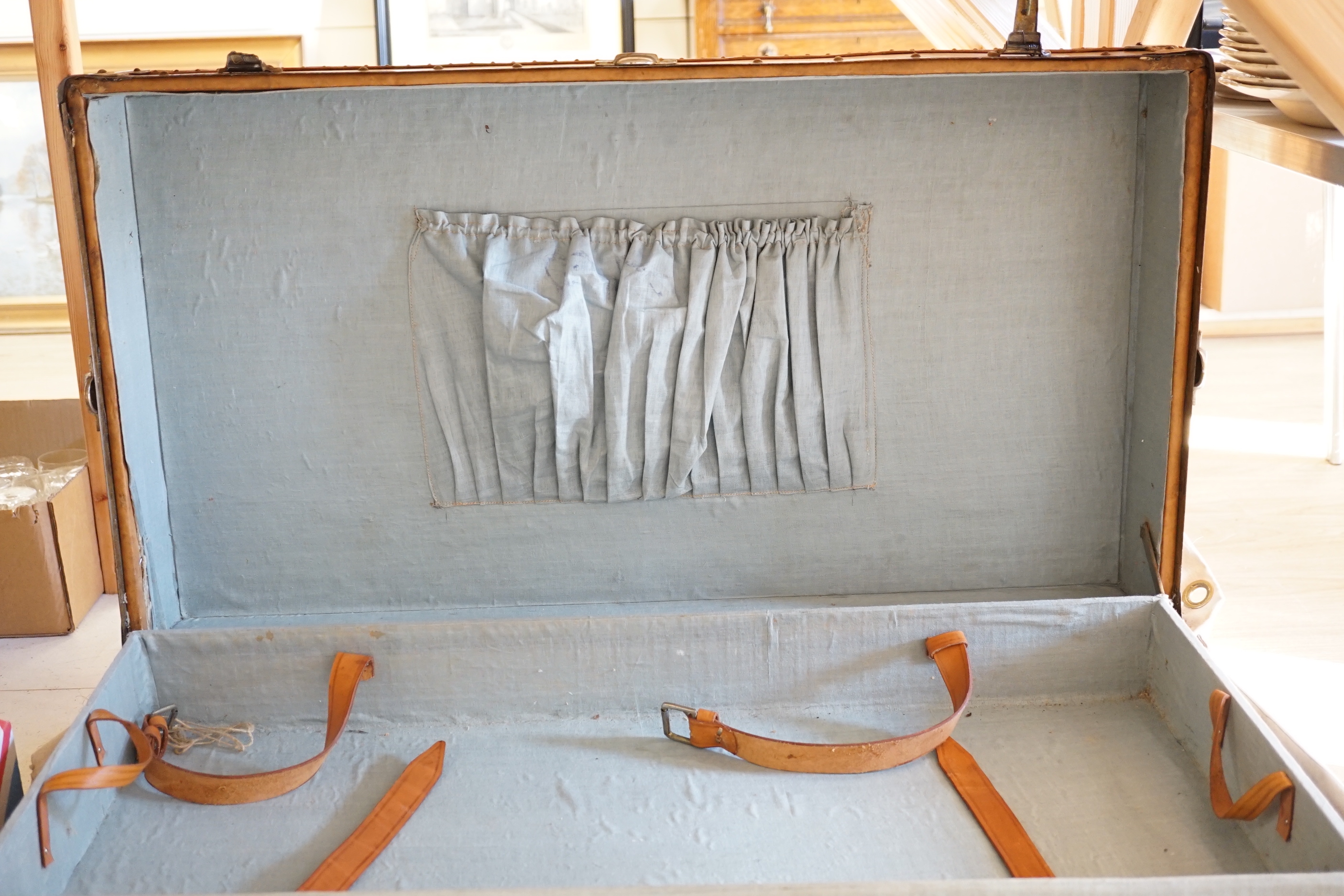 An early 20th century leather trunk, 90cm, in canvas outer wrapper